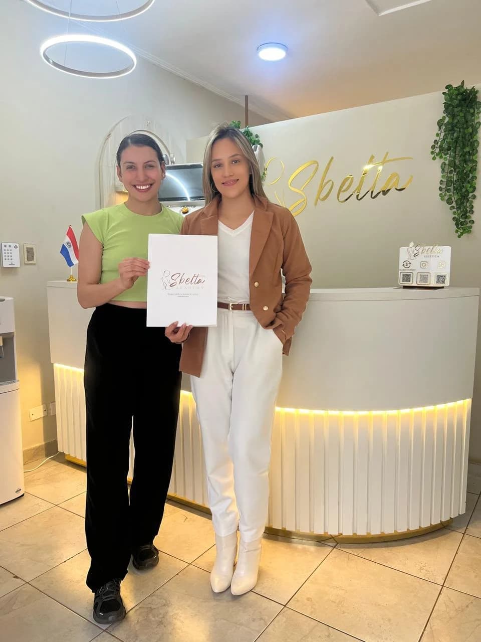Ruth Ortiz junto a una alumna sosteniendo una carpeta de Sbelta